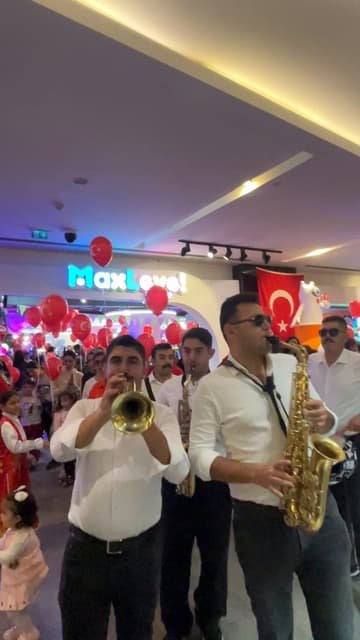 Aneva kortej bandosu, kırmızı balonlarla süslü alışveriş merkezinde trompet ve davulla yürüyor